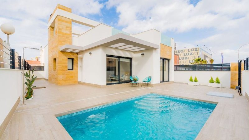 Une villa contemporaine et sa piscine, sous un ciel dégagé.