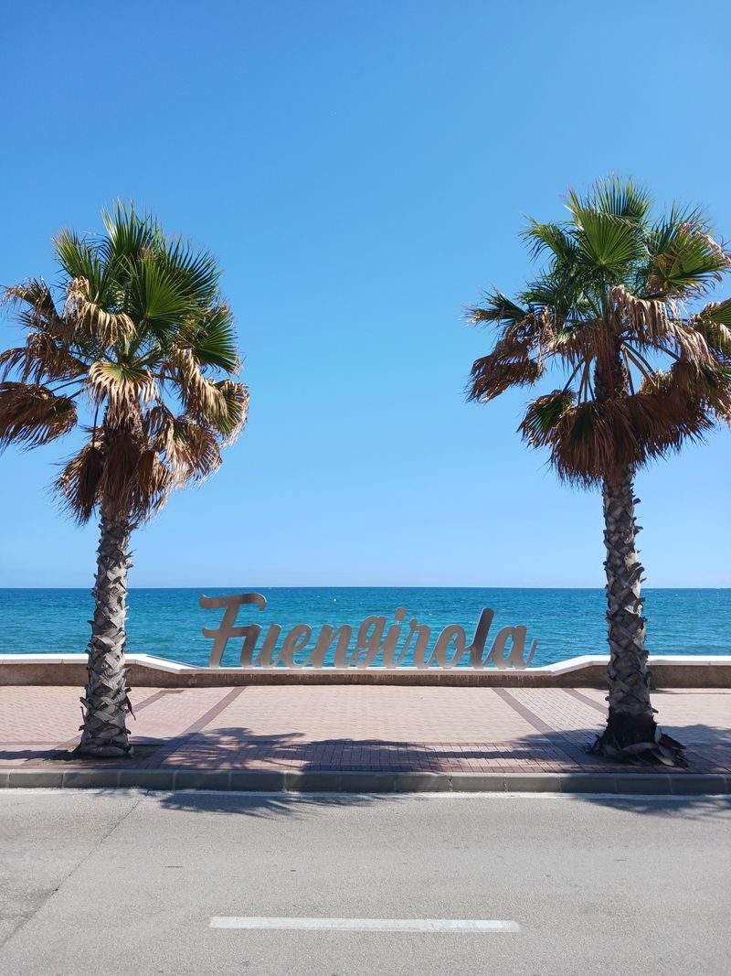 Het Fuengirola-bord op de zeeboulevard, tussen twee palmbomen